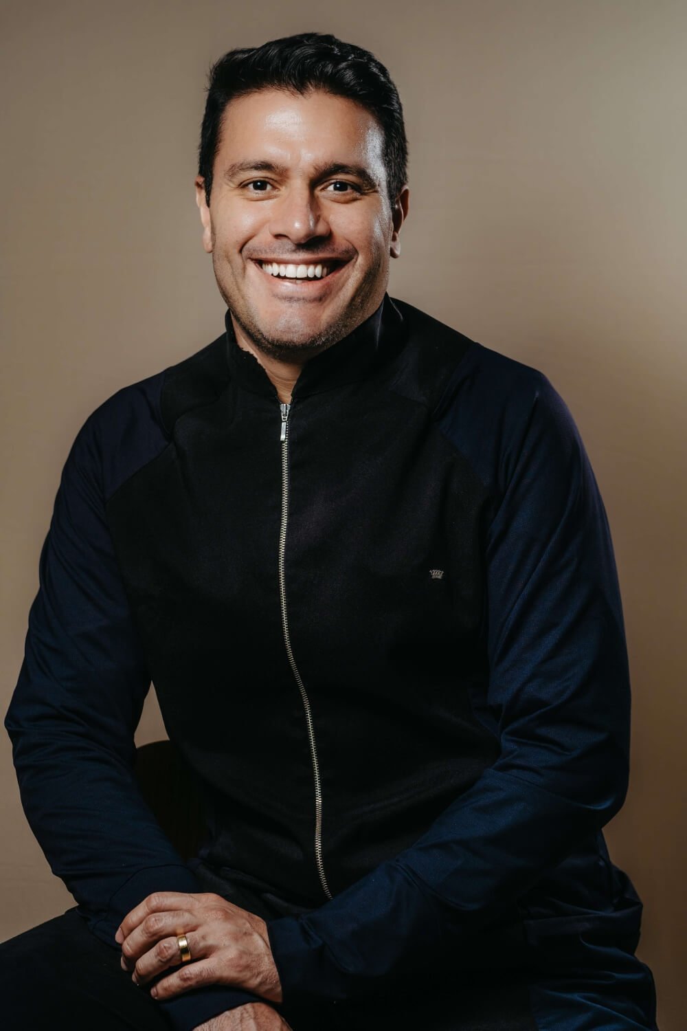 Dr carlos de jaleco azul escuro sorrindo para a camera. Dr carlos é especialiasta em implantes dentários, prótese protocolo, implante zigomático em Linhares ES