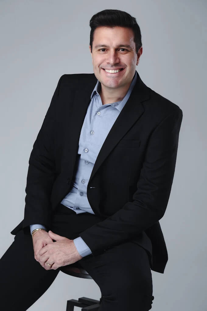 Dentista da clínica Spazio Vita sorrindo de terno preto, representando o especialista em lentes de contato dental em Linhares ES.