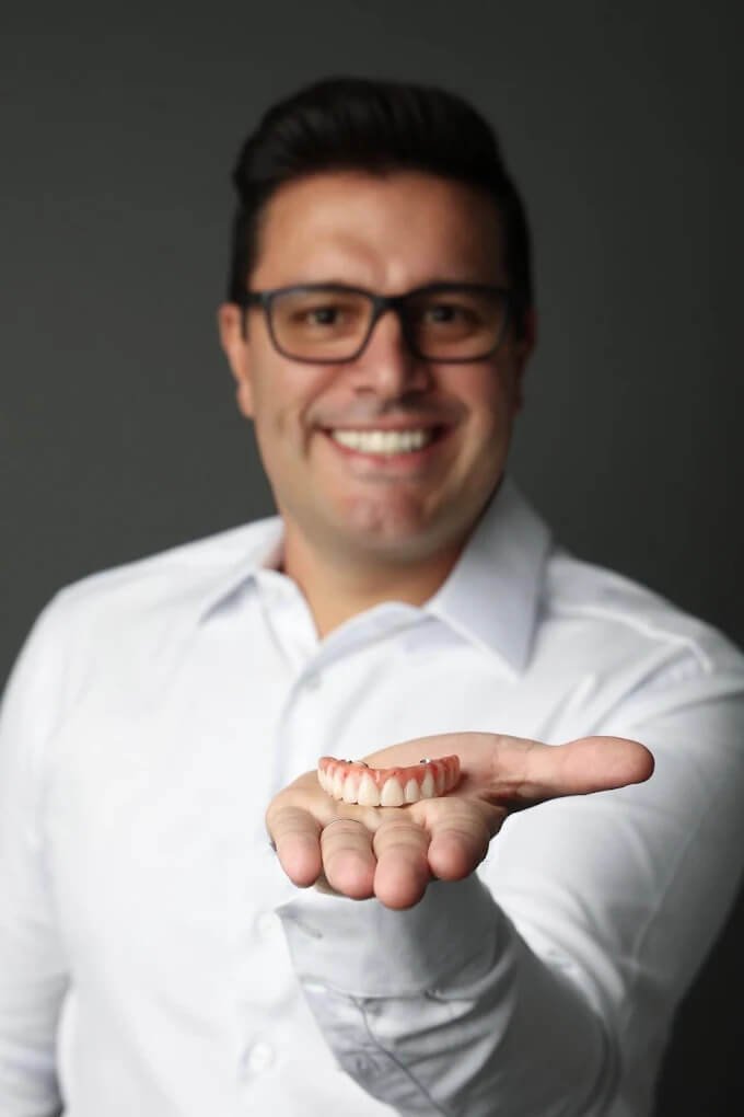 Dentista na Spazio Vita em Linhares ES segurando uma Prótese Protocolo em Linhares, apresentando a solução para reabilitação total do sorriso.